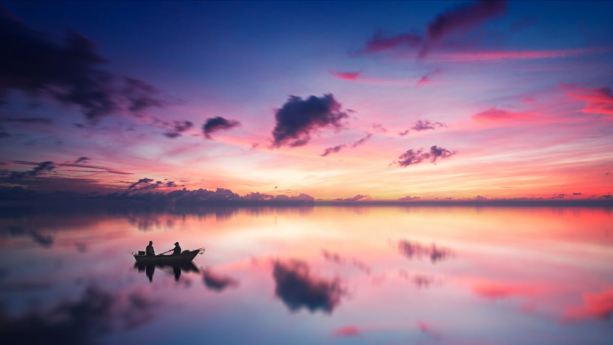 A boat on a lake with the sun beginning to rise behind it.